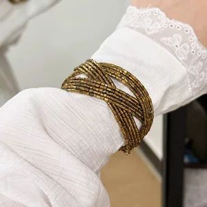 دستبند چندلایه مهرهدار طلایی به سبک Y2K و قدیمیپسند، با بافت فلزی کهنهنما و طرح زیرفرهنگی